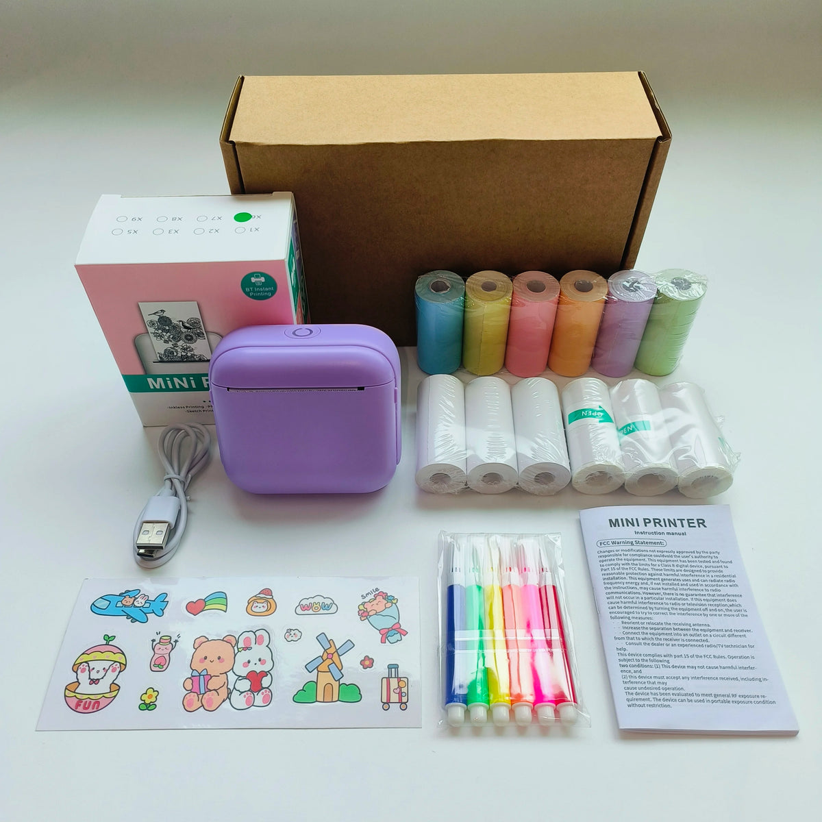 Mini portable printer with accessories including rolls of paper, markers, and packaging for versatile printing needs.